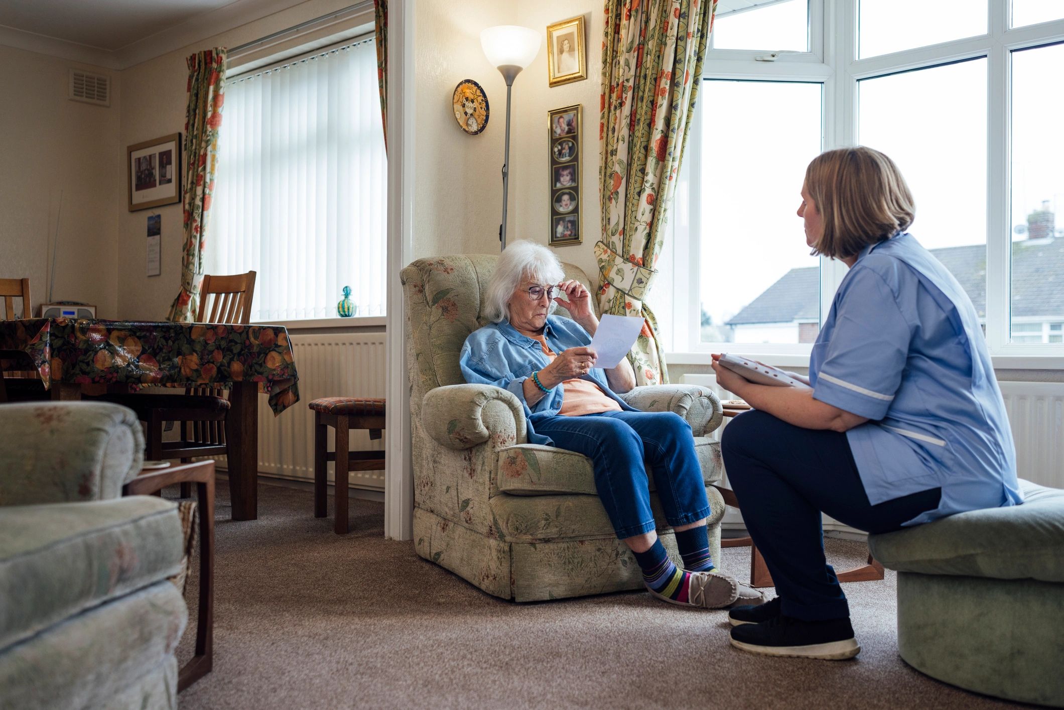 Home carer speaking with an older woman in her living room